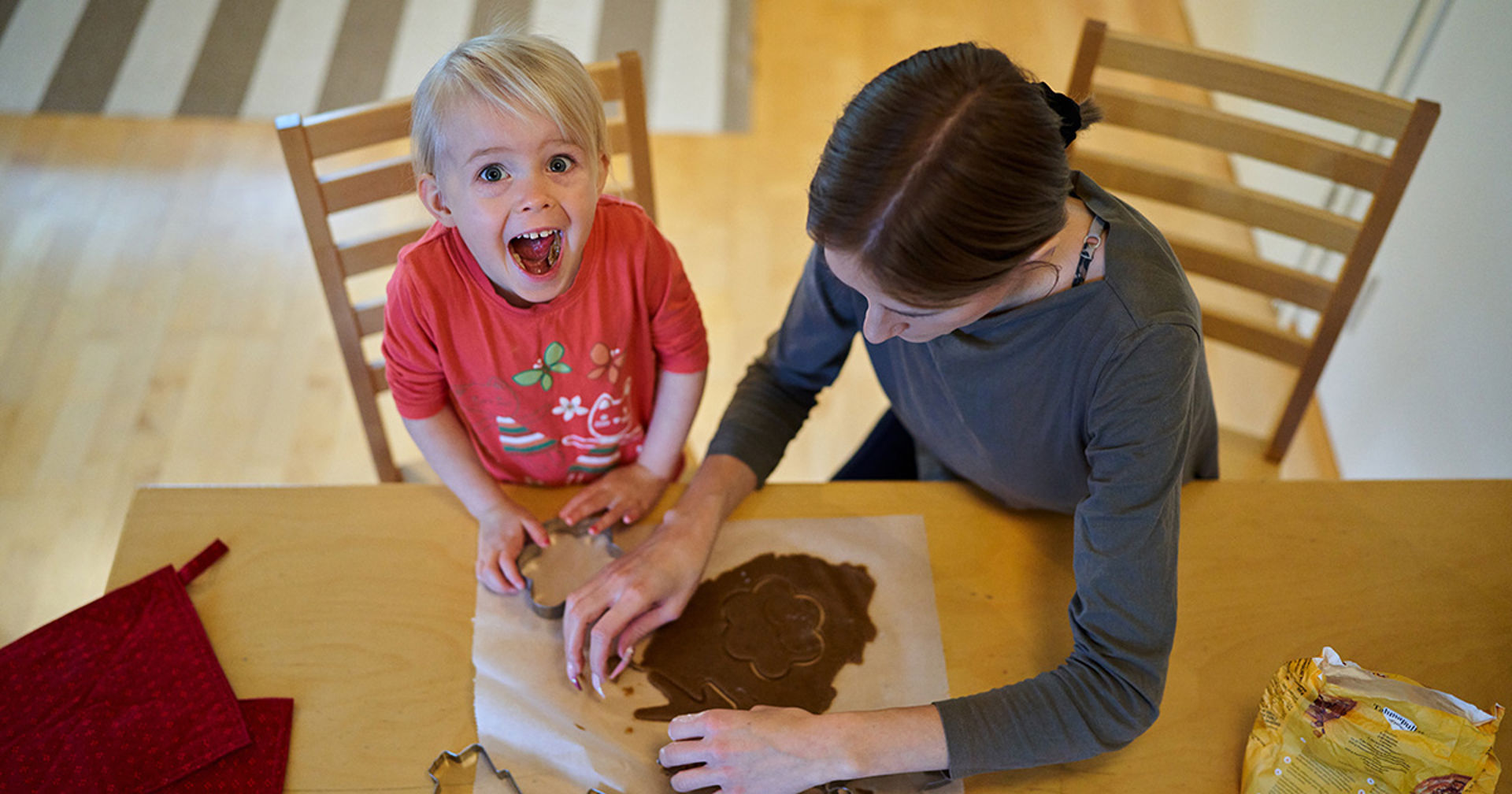 Ett leende barn bakar pepparkakor med sin mor.