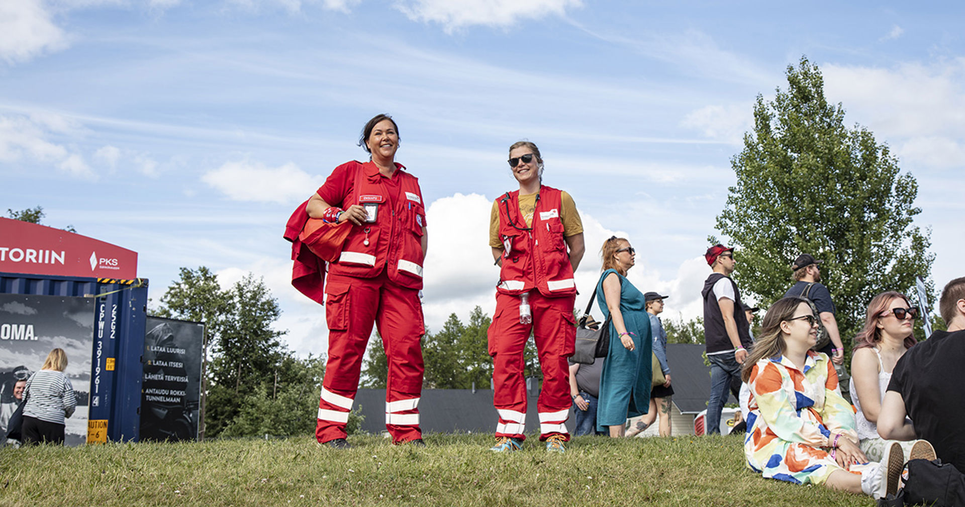 Två leende jourhavande i första hjälpen på en festival i sommarväder.