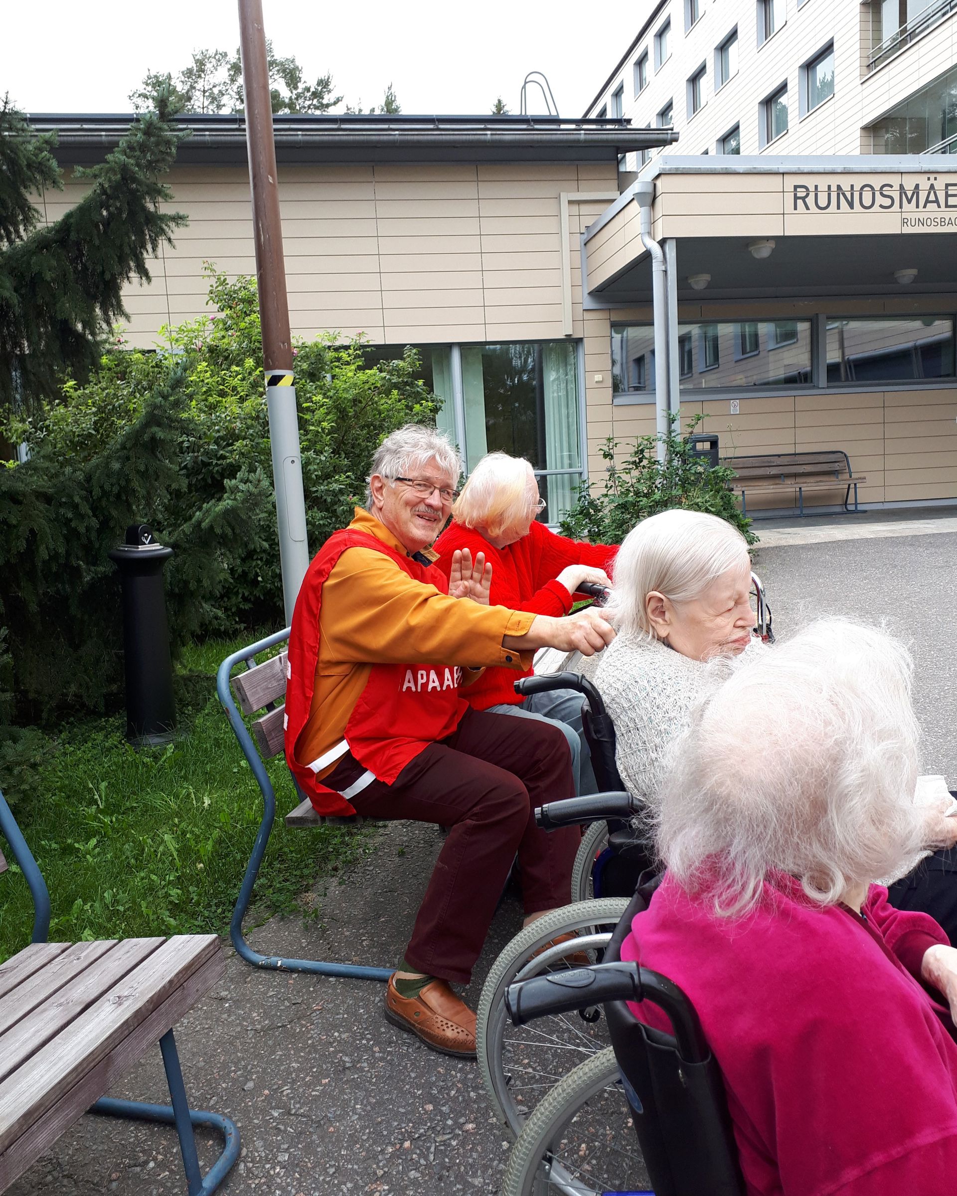 En leende frivillig från Röda Korset är ute med äldre boende från ett servicehus.