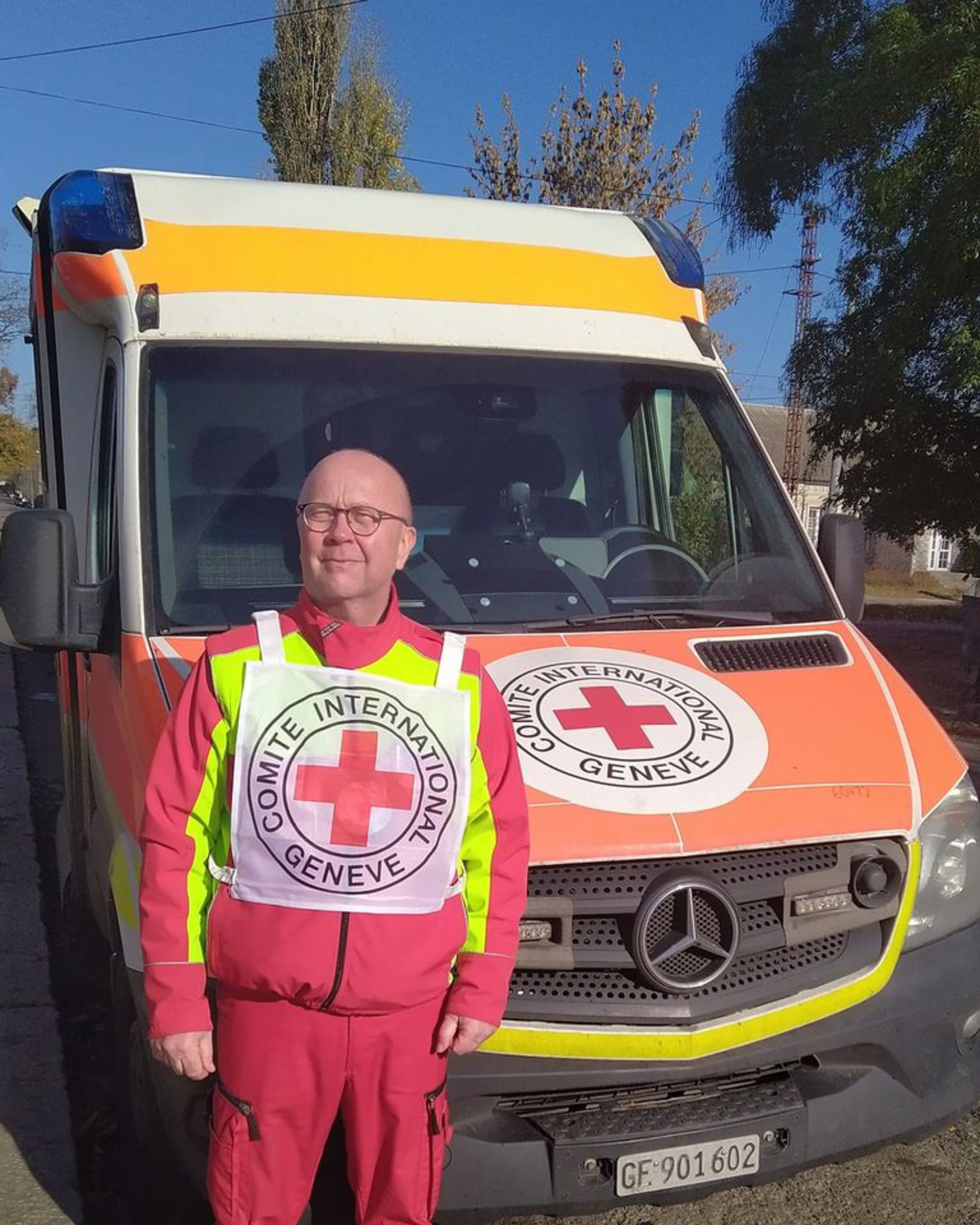 Primärvårdare Tuomo Hämäläinen ler bredvid Röda Korskommitténs ambulans